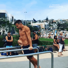 a shirtless man is doing exercises on a railing in front of a crowd of people including a woman in a bikini