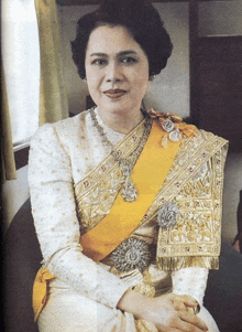 a woman wearing a white and gold dress with a yellow sash