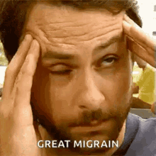 a man with a beard is holding his head in pain and says `` great migraine '' .