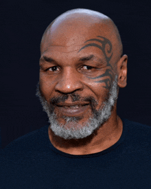 a man with a tattoo on his face is smiling for the camera