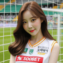 a girl wearing a soobet jersey stands in front of a soccer goal