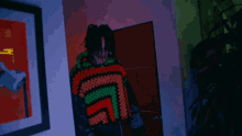 a man in a colorful sweater stands in a hallway