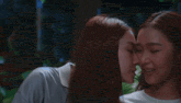 two women are kissing each other in front of a green background .