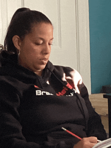 a woman wearing a black bra hoodie sits at a desk