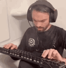 a man wearing headphones is typing on a computer keyboard .