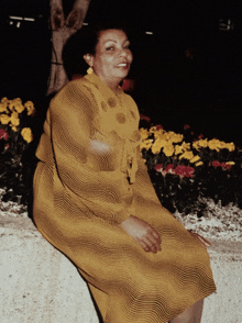 a woman in a yellow dress is sitting on a wall