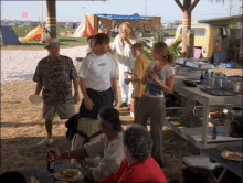 a group of people gathered around a table with a man wearing a shirt that says ' hawaiian ' on it