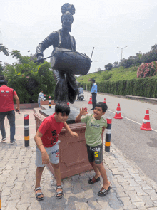 two young boys are standing in front of a statue with one wearing a shirt that says star 5