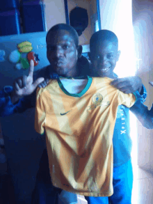 a man and a boy holding a yellow shirt that says nike on it