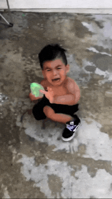 a young boy is crying while holding a green water gun