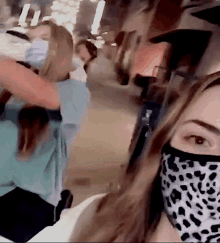 a woman wearing a leopard print face mask is standing next to another woman wearing a mask