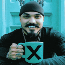 a man with a beard and mustache is holding a green mug with an x on it