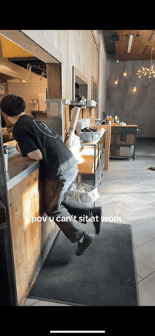 a man leaning against a counter in a restaurant with a caption that says ' pov u can t sit at work '