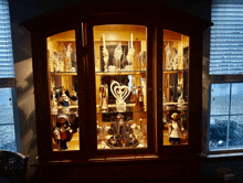 a glass hutch with a heart shaped candle holder in the middle