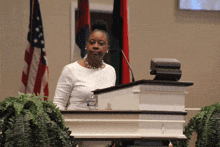 a woman stands behind a podium with a bottle of aquafina water on it