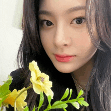 a close up of a woman 's face with a yellow flower in front of her