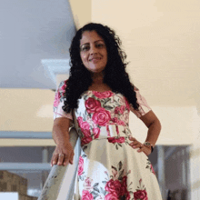 a woman wearing a pink and white floral dress stands on a staircase