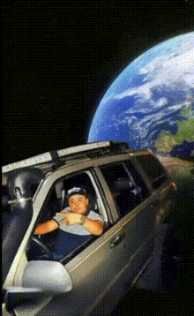 a man is sitting in a car with a large earth behind him