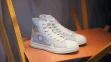 a pair of white high top sneakers are sitting on a wooden table