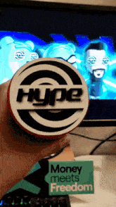 a person is holding a hype sticker in front of a television