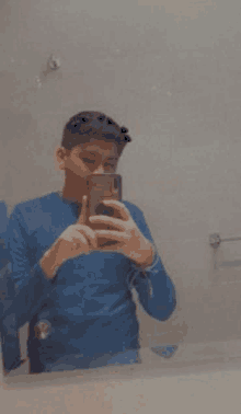 a young boy is taking a selfie in a bathroom mirror with his phone .