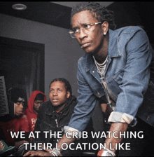 a man in a denim jacket stands in front of a group of men and says we at the crib watching their location