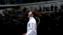 a man in a fencing uniform is dancing in front of a crowd with the olympics logo in the background