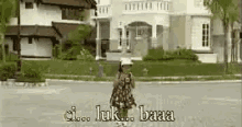 a woman is walking down a street in front of a large house .