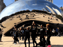 a group of people standing in front of a sculpture with one woman wearing a black shirt that says chicago