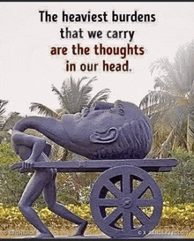 a statue of a man carrying a large head on a cart with a quote about the burdens we carry