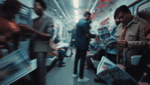 a man is reading a newspaper on a train that says ' the sun ' on the front