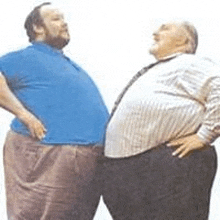 two fat men are standing next to each other and looking up .