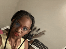 a girl wearing glasses and braids is giving a peace sign