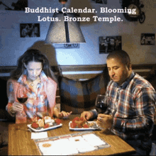 a man and a woman are sitting at a table with plates of food and a sign that says buddhist calendar blooming