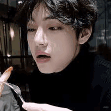 a close up of a young man eating a french fry with a fork .