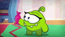 a green cartoon character is holding a pink candy in its hand