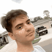 a young man with stars on his face is standing in a driveway