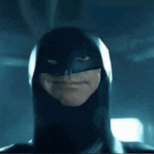 a close up of a person wearing a batman mask and a black suit .