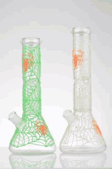 two glow in the dark glass bongs with spider webs on them