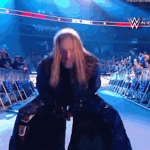 a woman is standing in front of a crowd in a wrestling ring with a wwe logo in the background