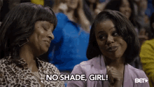 two women are sitting in a stadium and one is saying no shade girl