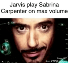 a close up of a man 's face with the caption jarvis play sabrina carpenter on max volume .