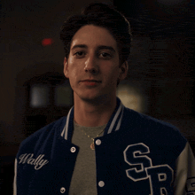 a young man wearing a blue varsity jacket that says wally