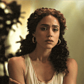 a woman with curly hair is wearing hoop earrings