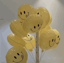 a bunch of yellow smiley face balloons hanging from a pole