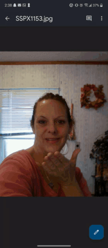 a woman blowing a kiss in front of a window with sspx1153.jpg in the corner