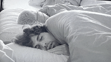 a man with curly hair is sleeping in a bed