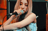 a woman is singing into a microphone with a ring on her finger