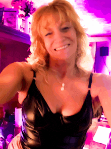 a woman in a black top is smiling and taking a selfie