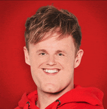 a young man wearing a red hoodie is smiling